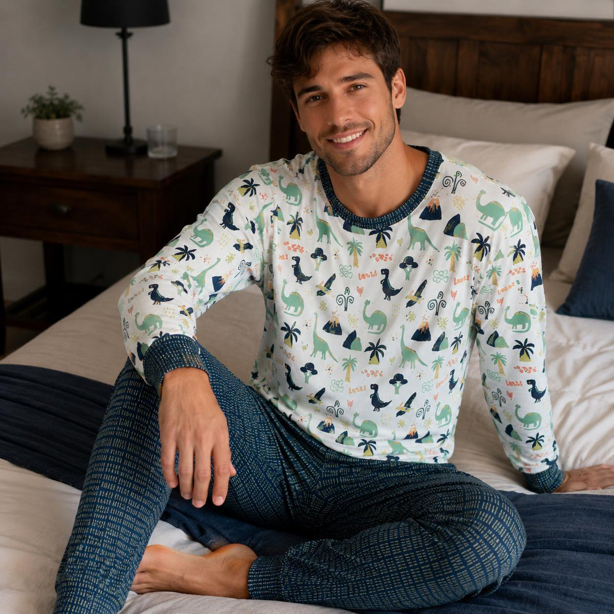 Man wearing two-piece ABDL pajama set with prehistoric dinosaur and volcano print top and dark blue patterned bottoms